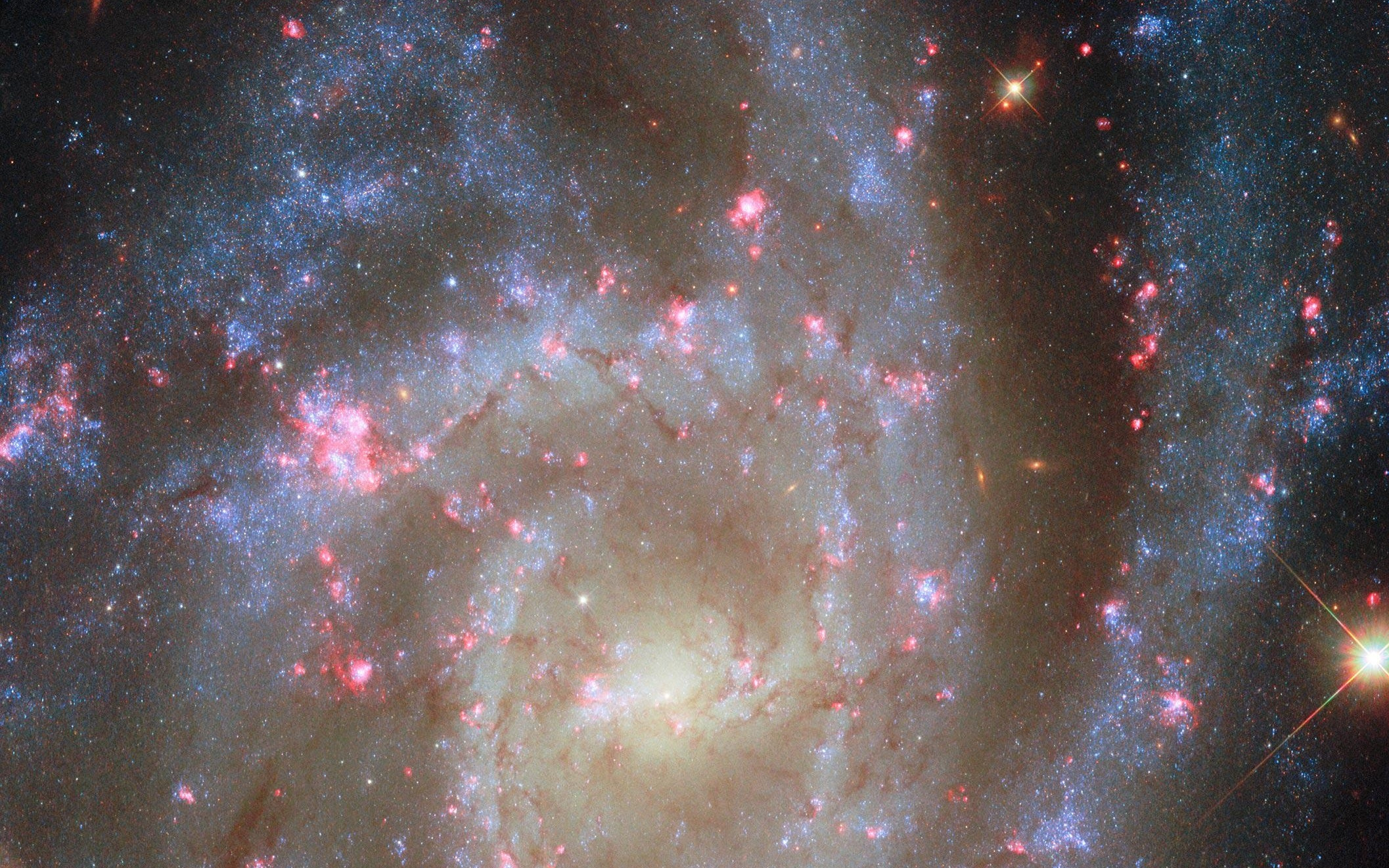 哈勃再秀宇宙美景：3500 万光年外螺旋星系粉色星云“绽放”