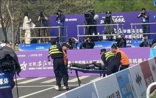 宇树H1机器人半马赛场终点“累倒”，现场视频：工作人员紧急用担架将其抬离